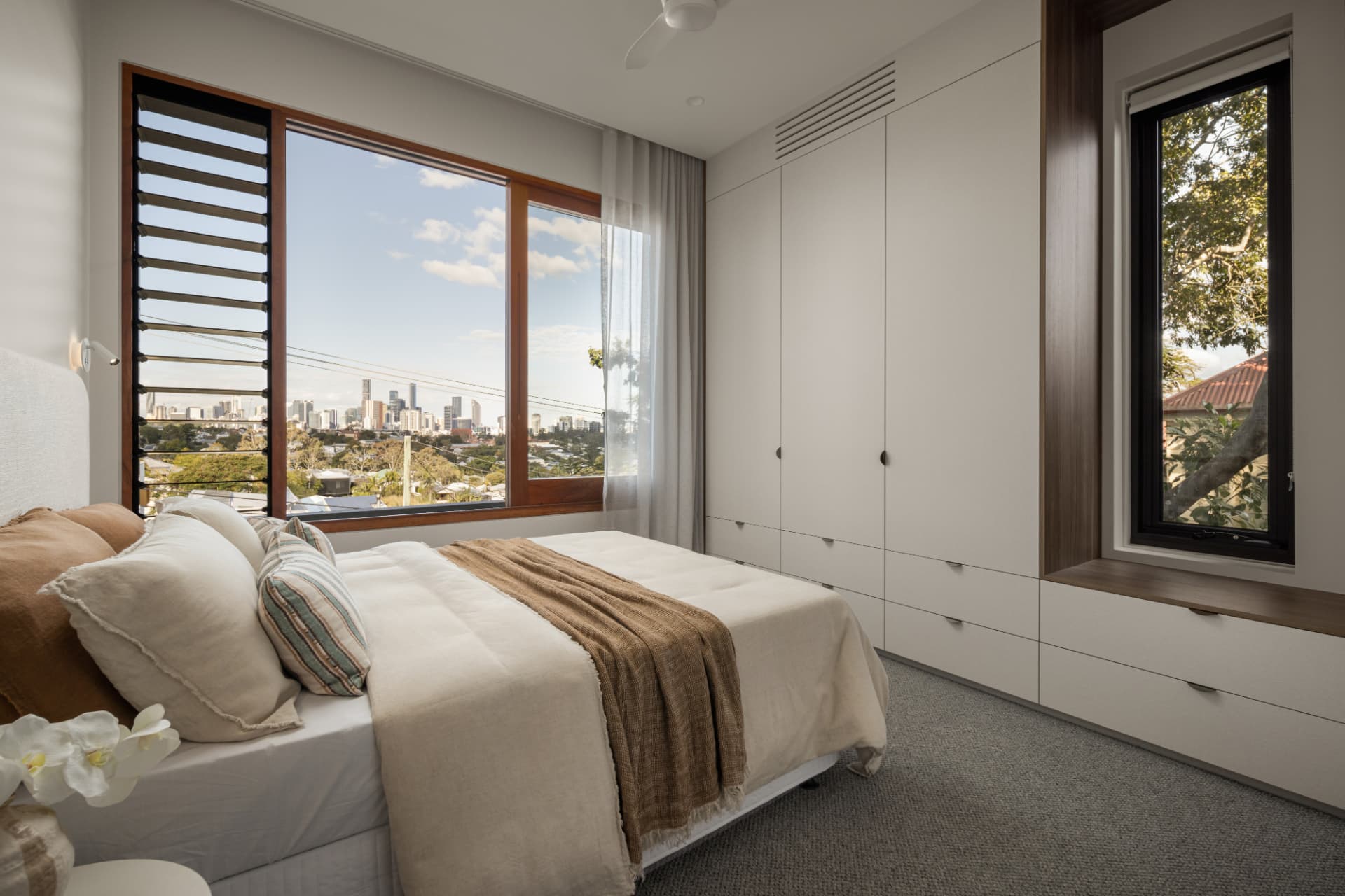 Guest bedroom with louvred windows and built-in joinery