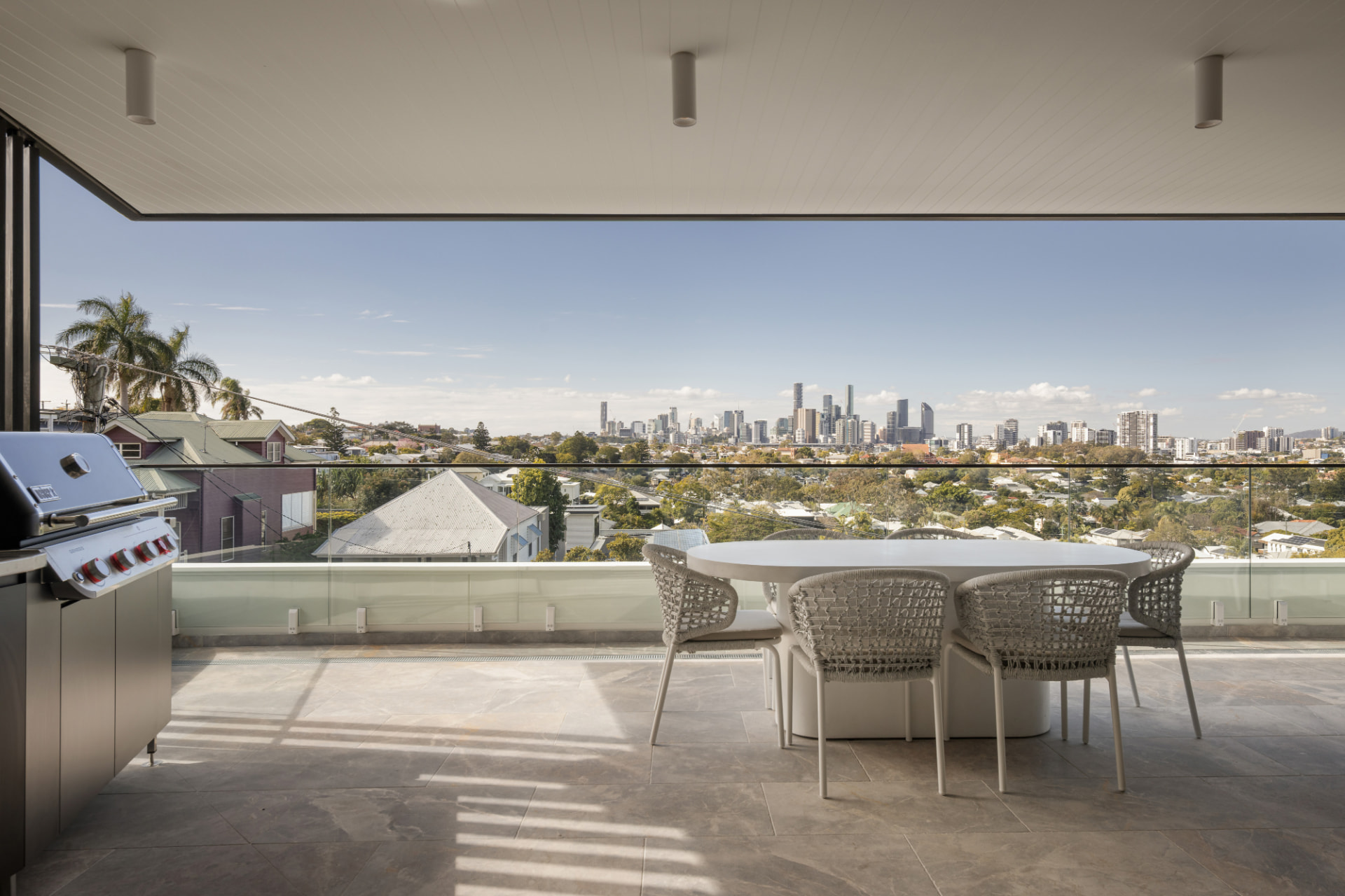Upper courtyard dining with stainless steel barbecue bench and Brisbane skyline