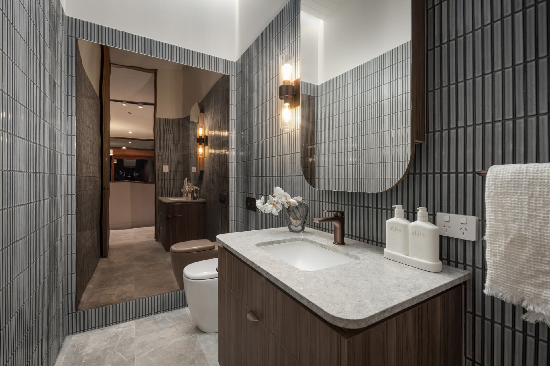 Powder room with fluted grey tiling and stone-topped vanity