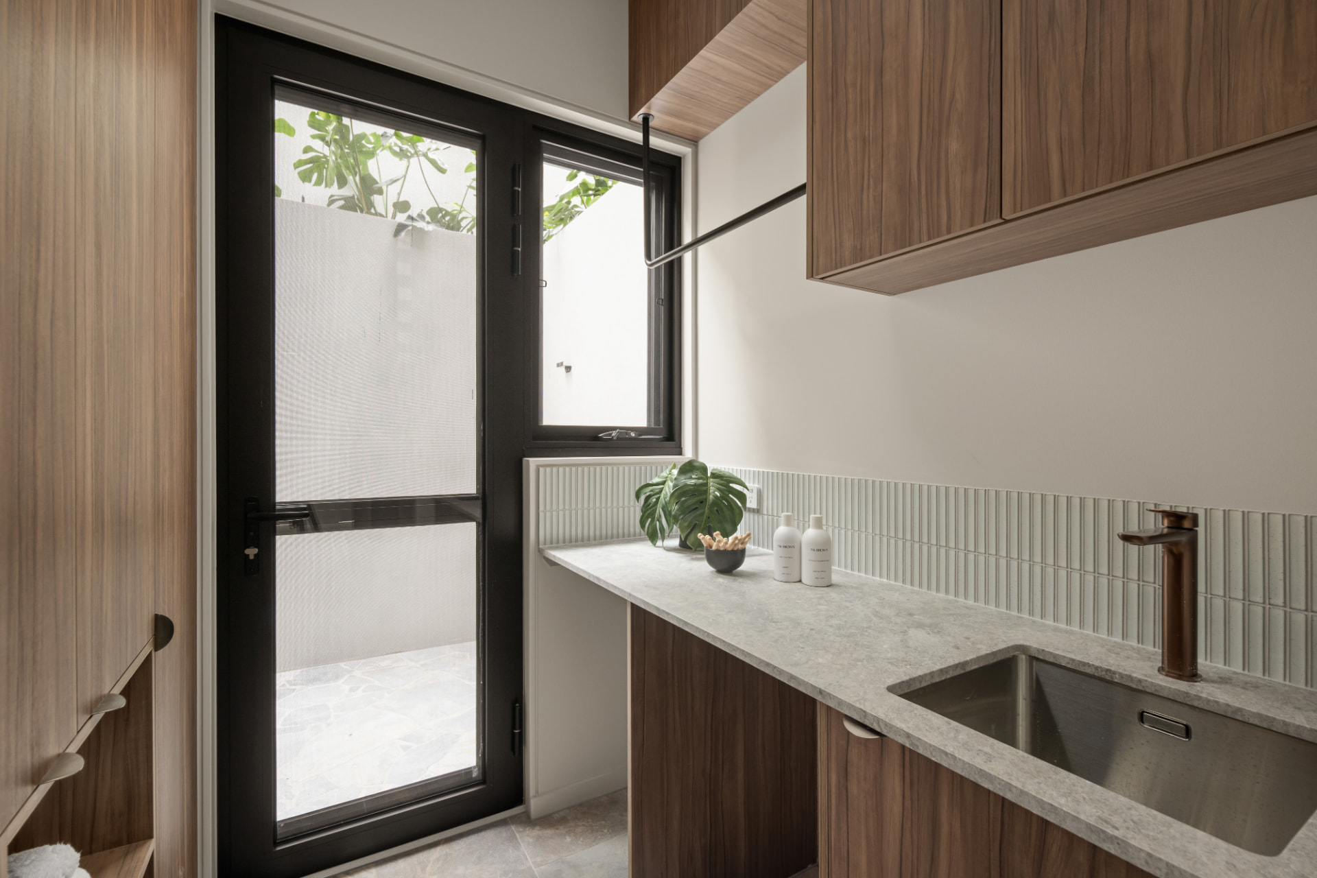 Laundry and service area with walnut joinery, stone benchtop and courtyard access